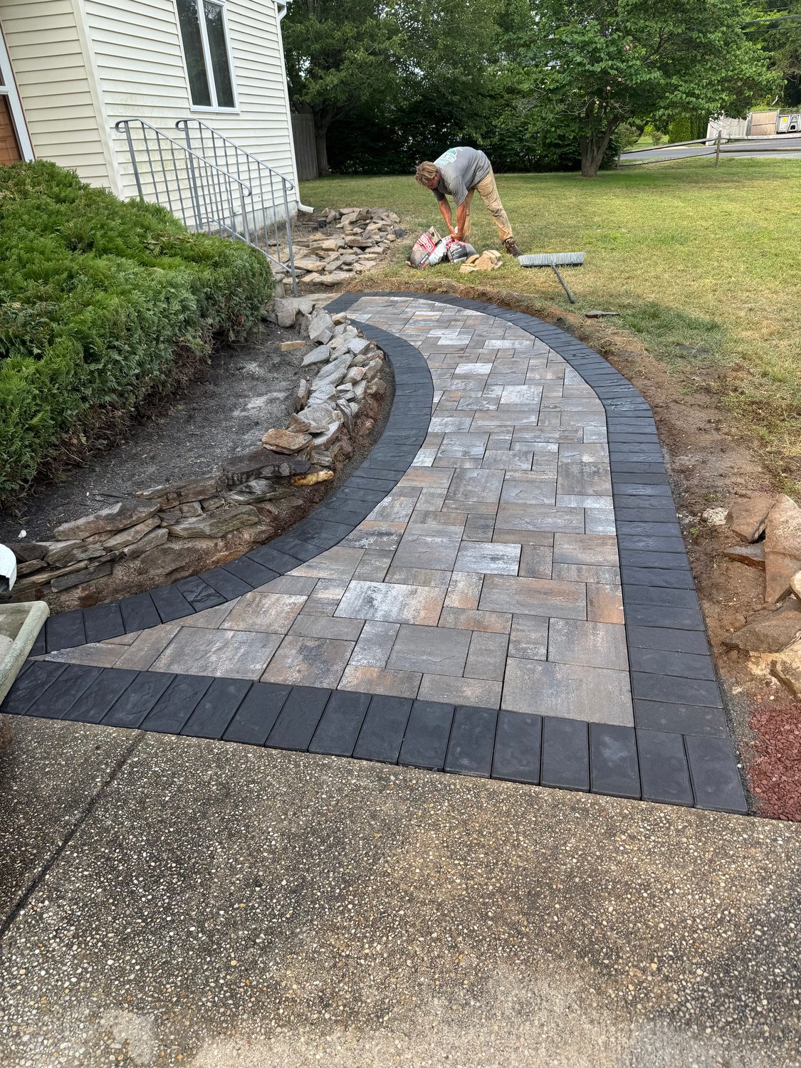 Curved paver walkway with a charcoal border and a natural stone edge leading to a lawn